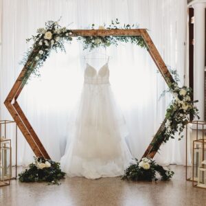 A picture of the wedding gown hanging on the wooden frame